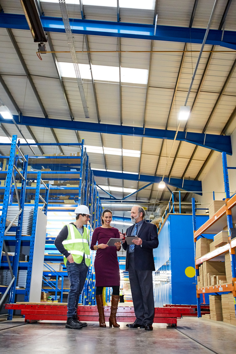Full length of businesswoman with senior businessman and warehouse worker. Business people holding digital tablets and discussing dispatch plan with warehouse worker.